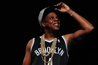 Hip-hop artist performing live at Barclays Center wearing a Brooklyn jersey and gold chains